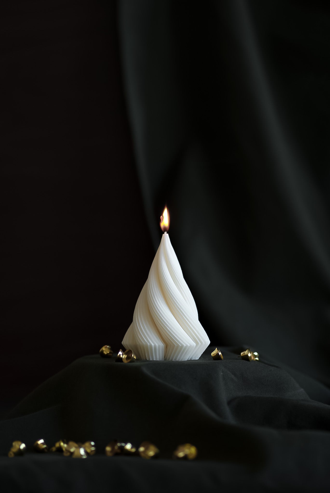 Handcrafted sculptural Christmas candle in a twisting design, made from eco-friendly European rapeseed wax by noosh.studio. Displayed against a dark background with gold holiday accents, perfect for Christmas home decor or gifting.