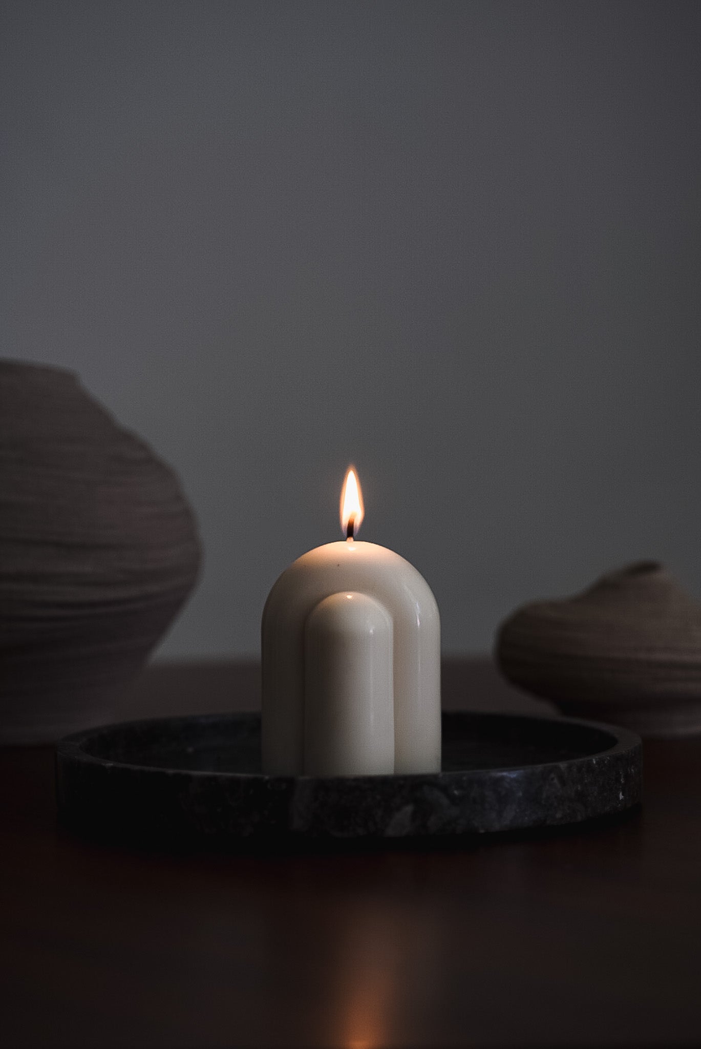 Handcrafted minimalist candle with a smooth arched design, made from eco-friendly European rapeseed wax by noosh.studio. Displayed on a dark tray, offering a modern and elegant aesthetic for home decor