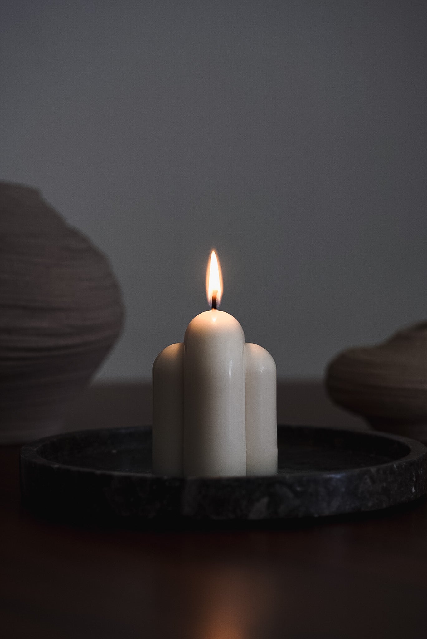 Handcrafted minimalist candle with a smooth arched design, made from eco-friendly European rapeseed wax by noosh.studio. Displayed on a dark tray, offering a modern and elegant aesthetic for home decor