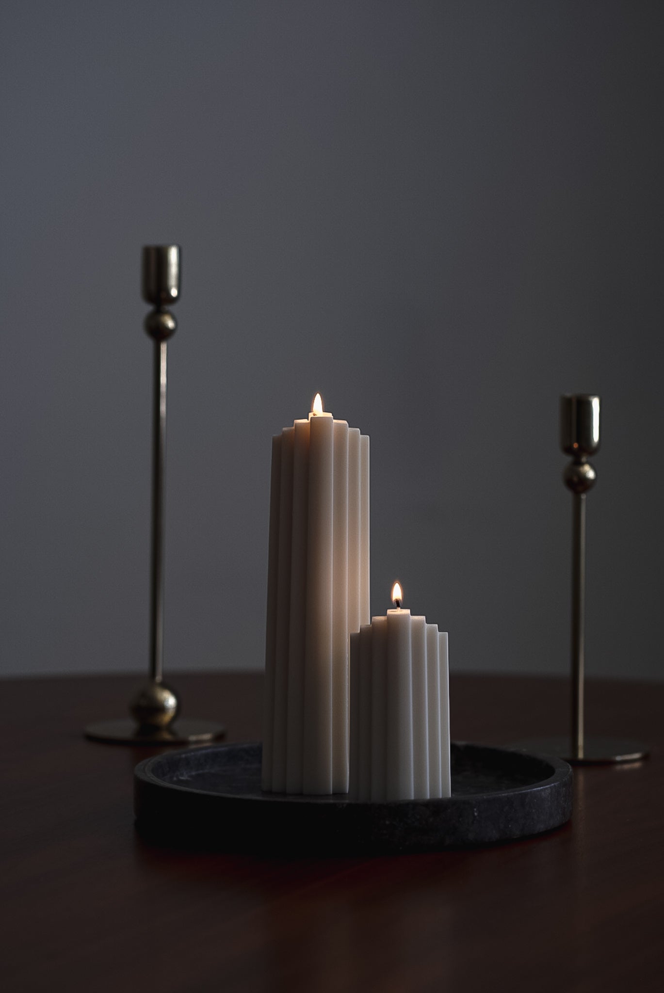 Two handcrafted geometric candles made from eco-friendly European rapeseed wax, designed by noosh.studio in Switzerland. Displayed on a dark tray, these minimalist, sculptural candles offer a modern aesthetic for home decor.